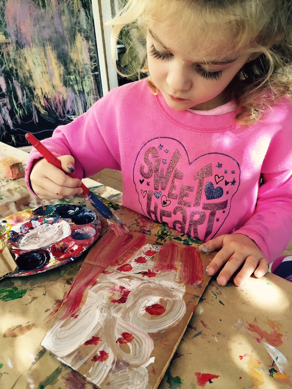 Preschool girl painting on cardboard
