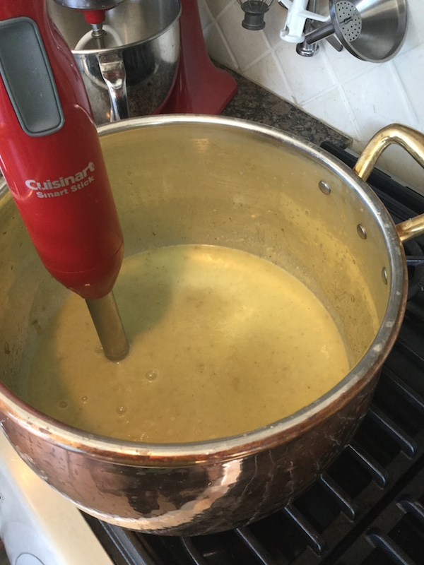 Immersion blender being used in pot to make potato leek soup