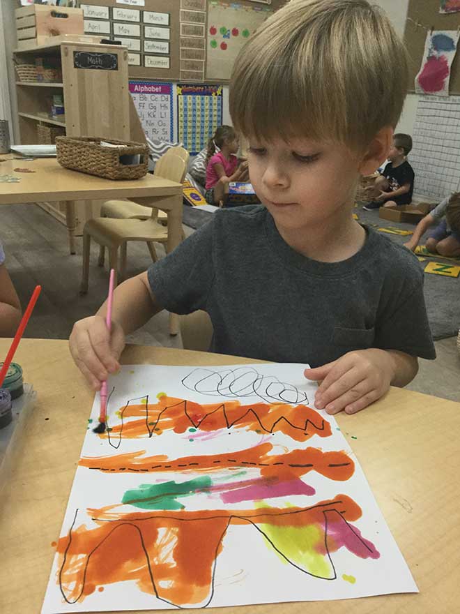 Young boy draws with paint and marker