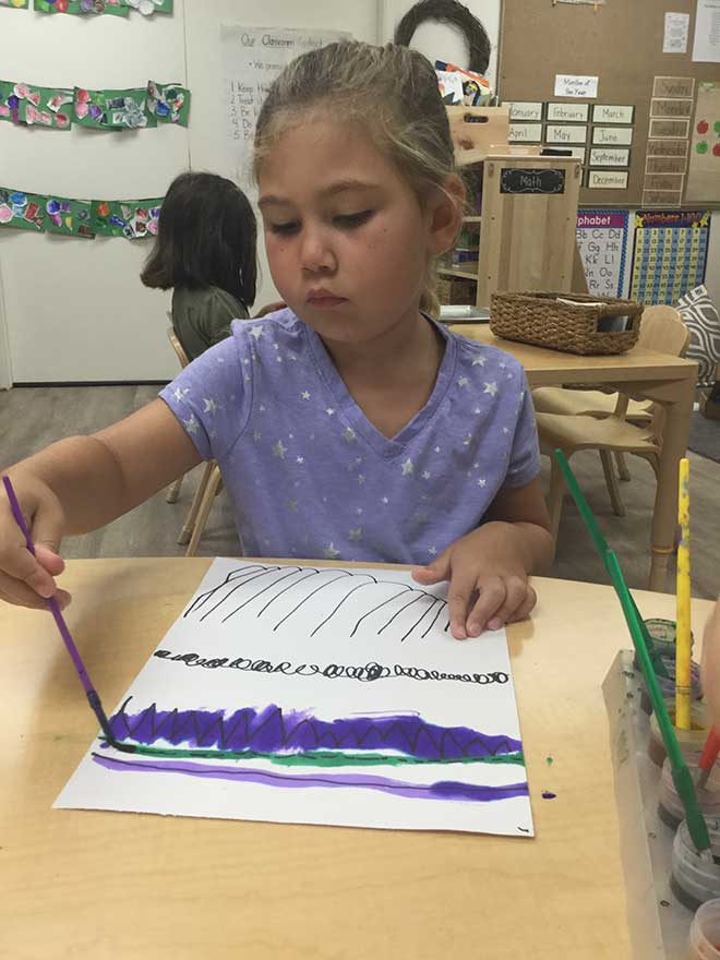 Young girl draws with paint and marker