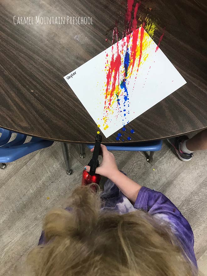 Toddler making spray art at our child care center