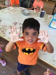 Little boy with flour on his hands as he experiments with a messy art lesson in the studio. The studio is a unique art studio to our childcare center.