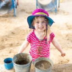 young girl playing in sand with buckets