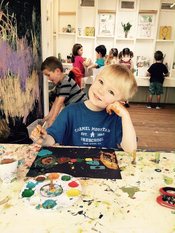 Blonde preschool boy painting in art class