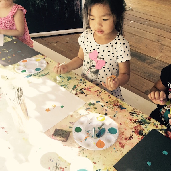 Preschool girl creating art with tools and paint