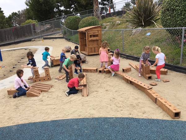 Kids using large outdoor woodblocks at CMP to build on playground