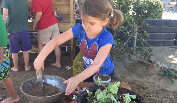 girl playing in mud kitchen