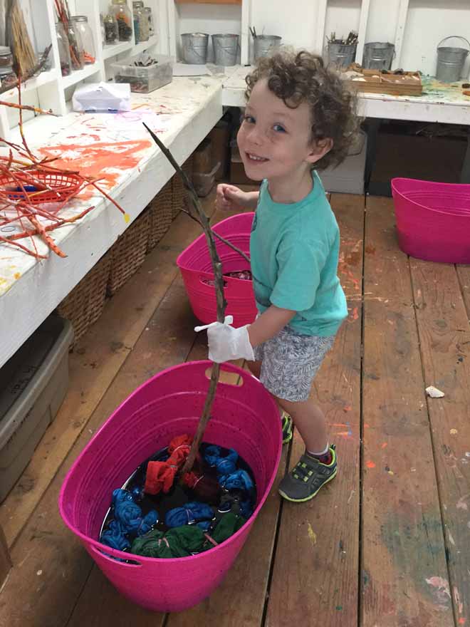 Carmel Mountain Preschool student mixing up the shirts in the dye!