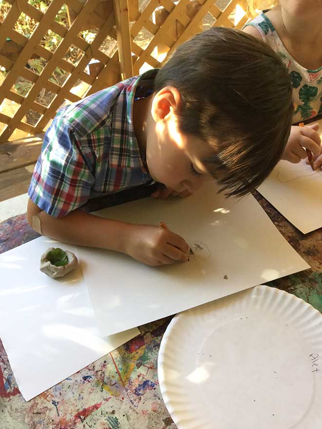 Toddler boy draws a design for a bird house