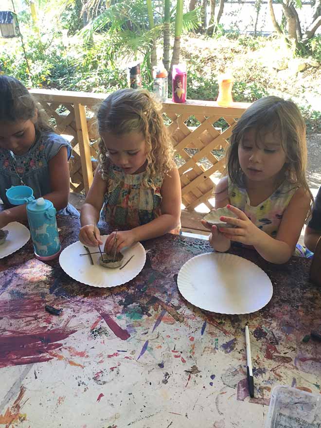 Toddler girls working on clay birdhouses