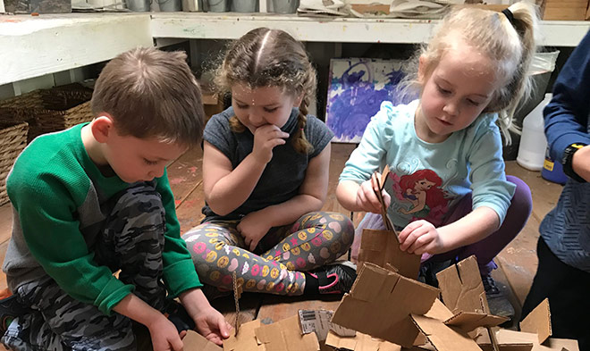 Toddlers piece together cardboard sculptures at our childcare center