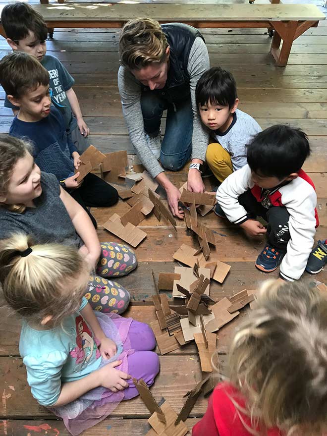 teacher shows kids how to make cardboard sculptures