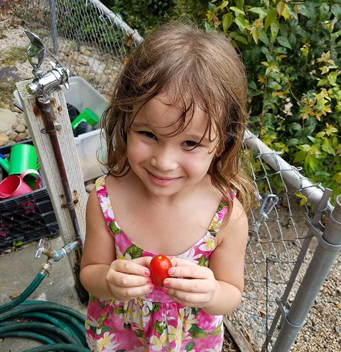 girl proud of the tomato she grew