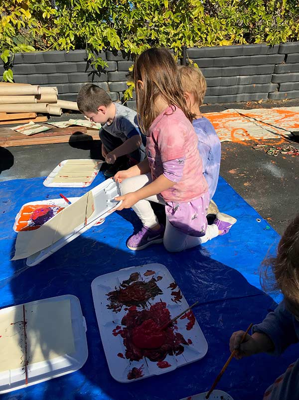 Toddlers playing with paint and art outside