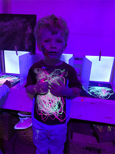 boy with art in glow room at child care center