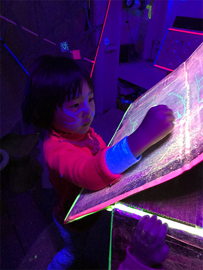 girl drawing with chalk at daycare center in dark room