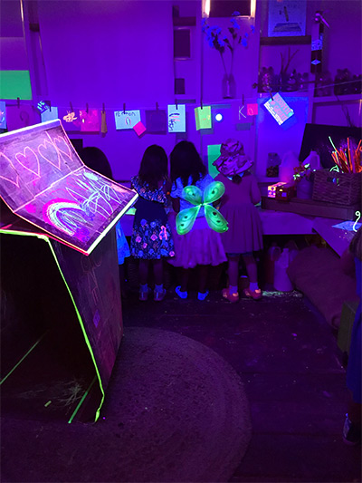 girls drawing in glow room at preschool