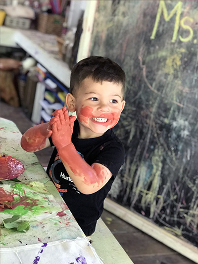 happy toddler playing with paint at preschool