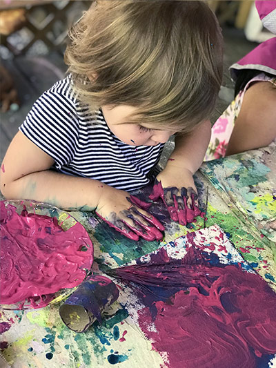toddler girl creating with paint at preschool