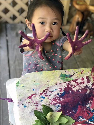 toddler playing with paint at daycare center