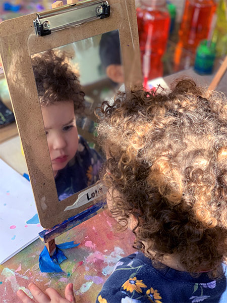 boy looking in mirror at daycare