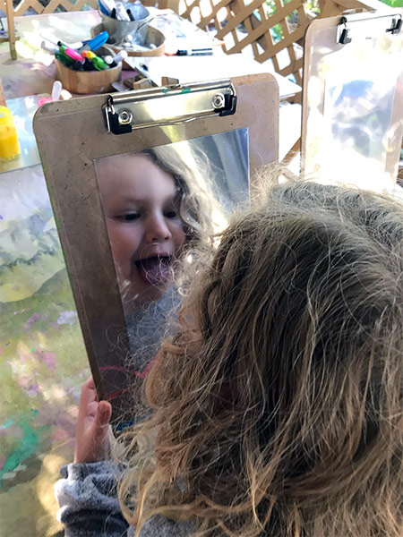 little girl looking in mirror at child care