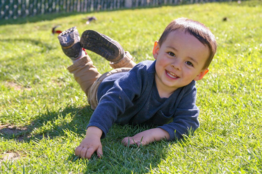 boy playing in grass at preschool