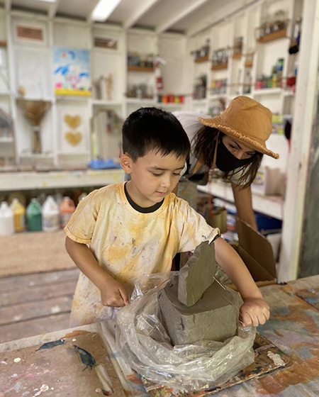 boy cutting clay at preschool