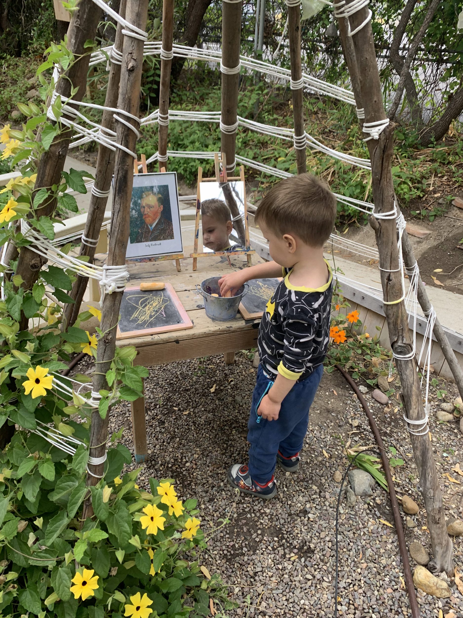 boy outside painting art at preschool