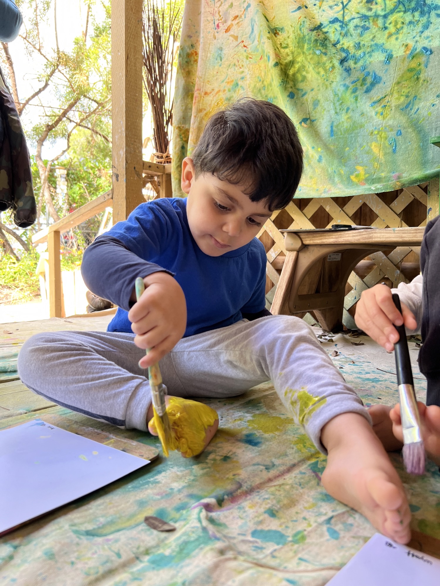 young boy painting his feet at preschool
