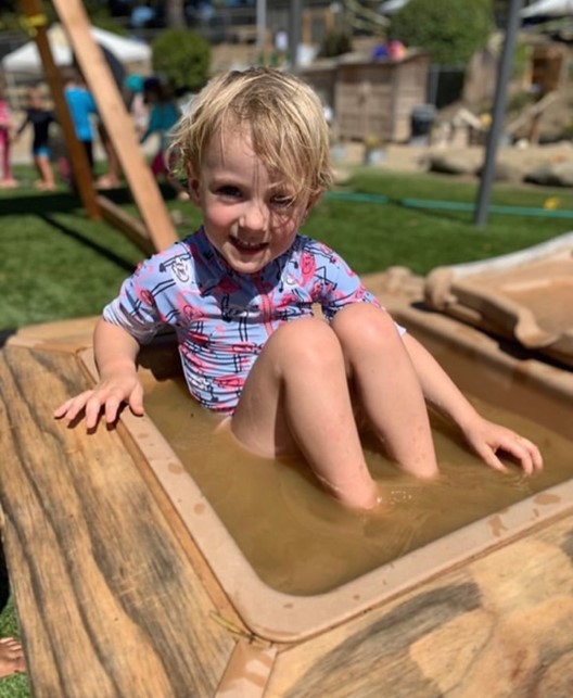 boy sitting in mud bath at preschool