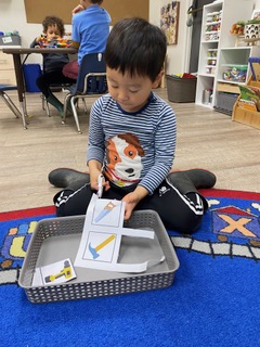young boy cutting with scissors at preschool