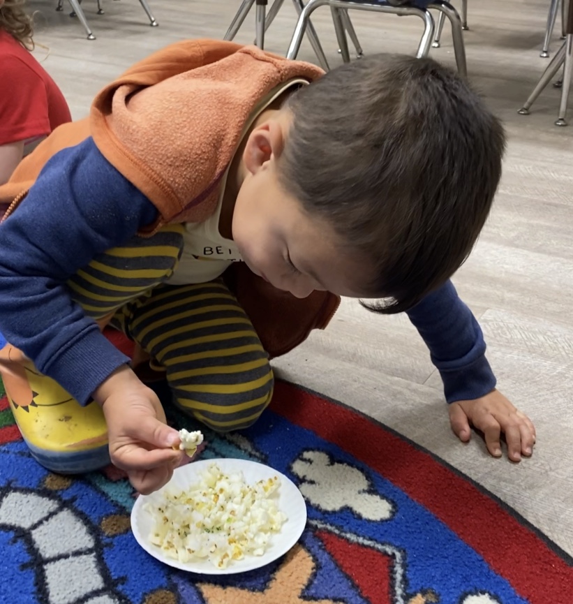young boy with eating popcorn at preschool