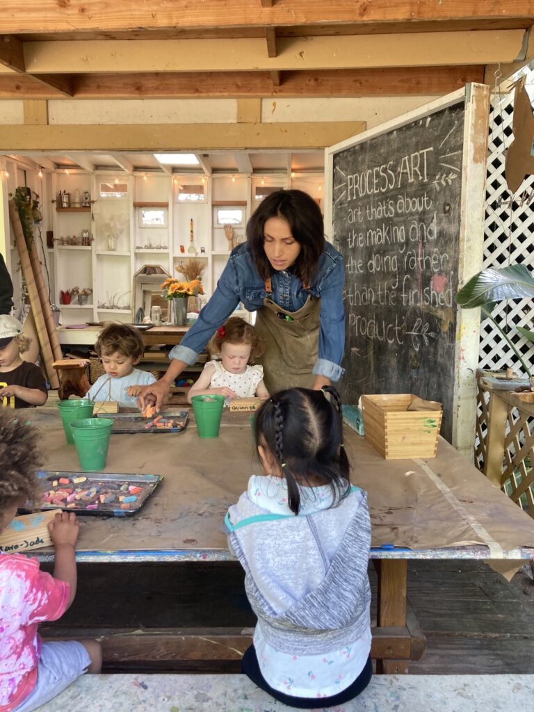 teacher helping students with art at preschool