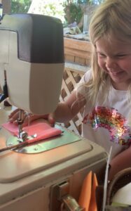 girl using sewing machine at preschool