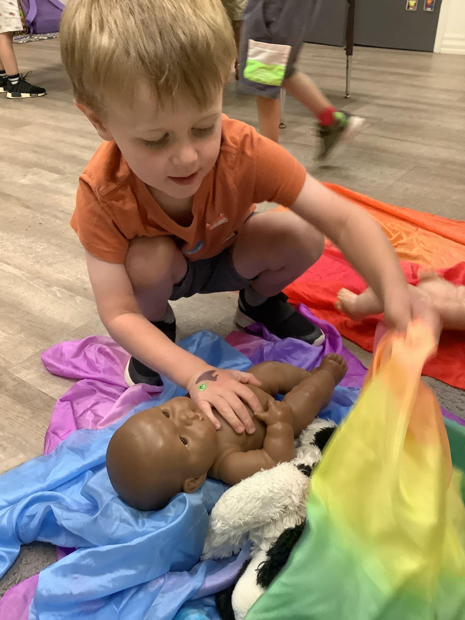 toddler with baby doll at preschool