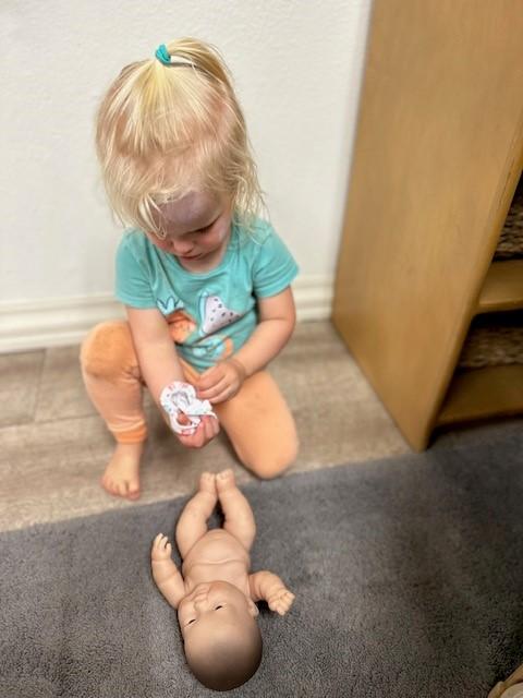 young toddler girl with baby doll at preschool