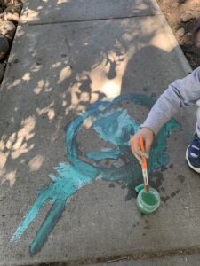 boy creating chalk art on sidewalk at preschool