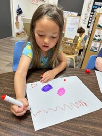girl painting to music at preschool