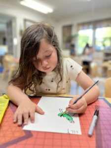 girl drawing water color dinosaurs at preschool