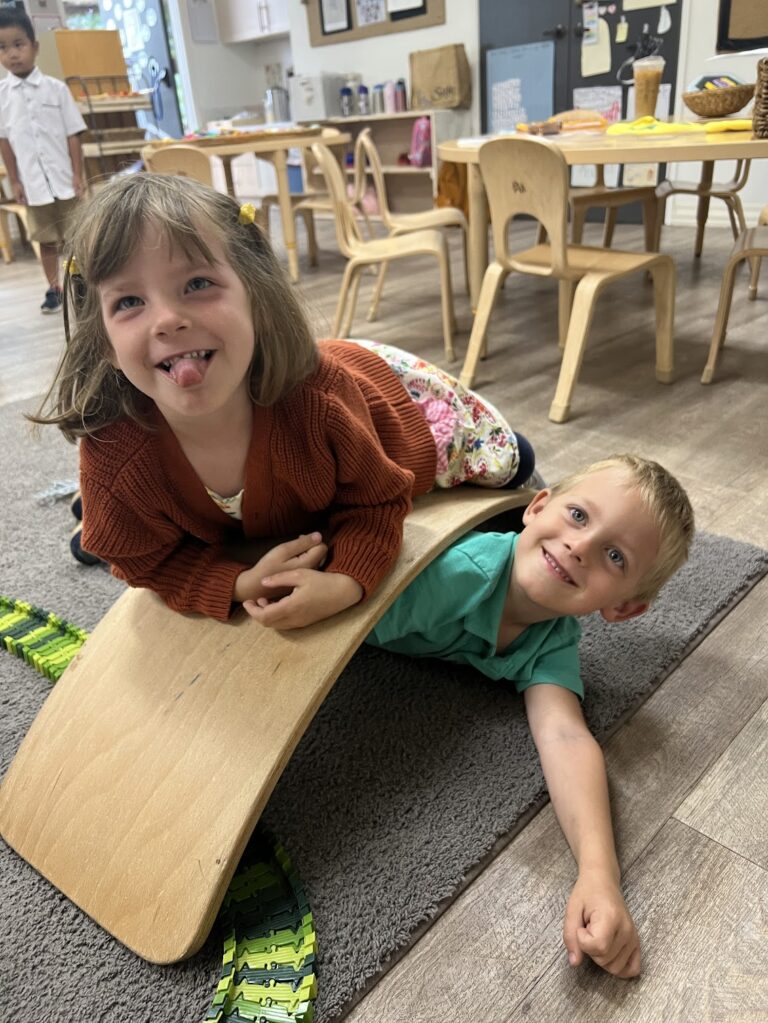 preschoolers smiling while playing on classroom floor