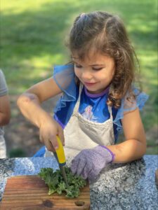 girl chopping vegetables at preschool